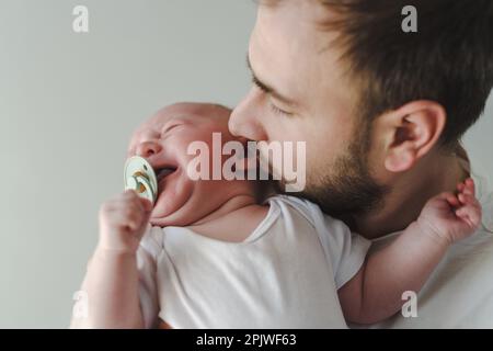 3 Monate altes Baby schreit und Vater versucht, sich zu beruhigen Stockfoto