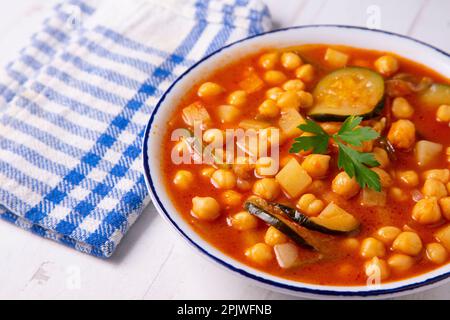 Typisch spanisches Gericht mit Kichererbseneintopf mit Gemüse wie Karotten, Paprika oder Zucchini. Stockfoto