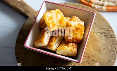 Kleines, quadratisches Blätterteiggebäck mit Gratinkäse. Stockfoto