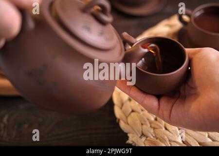 Teezeremonie. Traditionelles Asiatisches Teeutensil, Serviert Authentisches Set. Person, die Tee von der Teekanne aus brauner Keramik bis zur Teekanne einschenkt. Bambusschale. Lifestyle. Wir Stockfoto