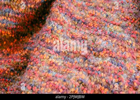 Warmer, farbenfroher Strickpullover oder Schal. Gemütliche Komposition in der häuslichen Atmosphäre, warme Farben. Wollstruktur Nahaufnahme des Hintergrunds. Bequem Stockfoto