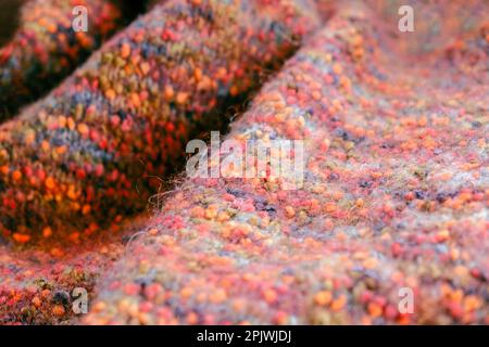 Warmer, farbenfroher Strickpullover oder Schal. Gemütliche Komposition in der häuslichen Atmosphäre, warme Farben. Wollstruktur Nahaufnahme des Hintergrunds. Bequem Stockfoto