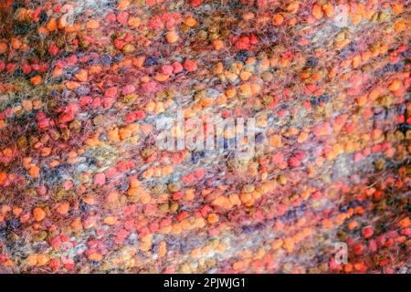 Warmer, farbenfroher Strickpullover oder Schal. Gemütliche Komposition in der häuslichen Atmosphäre, warme Farben. Wollstruktur Nahaufnahme des Hintergrunds. Bequem Stockfoto