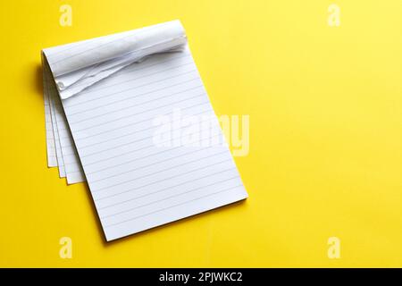 Draufsicht eines leeren offenen Notizbuchs mit zerrissenen Seiten. Seite mit Linien auf gelbem Hintergrund und Kopierbereich. Zur Verwendung als Modell oder Vorlage. Stockfoto