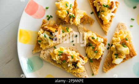 Rührei mit Eiern und Pilzen auf getoastetem Brot. Stockfoto