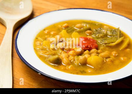 Typisch spanisches Gericht mit Kichererbseneintopf mit Gemüse wie Karotten, Paprika oder Zucchini. Stockfoto