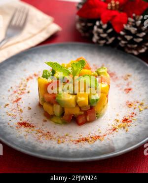 Avocado, Mango und Tomatentartare auf einem Tisch mit Weihnachtsdekorationen. Stockfoto