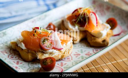 Zwei Toasts mit Bio-Brot, Frischkäse, Radieschen und geräuchertem Lachs. Stockfoto