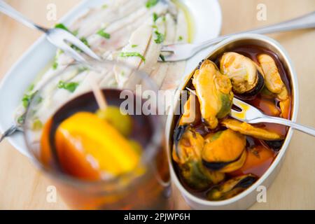 Vermouth ist ein in Kräutern mazerierter Wein, der als Aperitif mit Cockeln, Sardellen, Oliven oder Muscheln eingenommen wird. Stockfoto