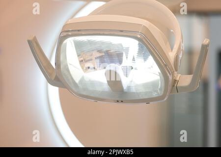 Nahzahnarztkliniklampe mit verschwommenem Zahnarztpraxiskonzept. Selektivfokus der Zahnarztlampe. Offener Raum. Stockfoto