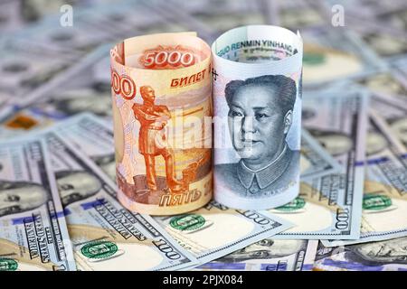 Chinesische Yuan-Banknote und russischer Rubel mit US-Dollar-Hintergrund. Konzept der strategischen Partnerschaft zwischen China und Russland, wirtschaftlich Stockfoto