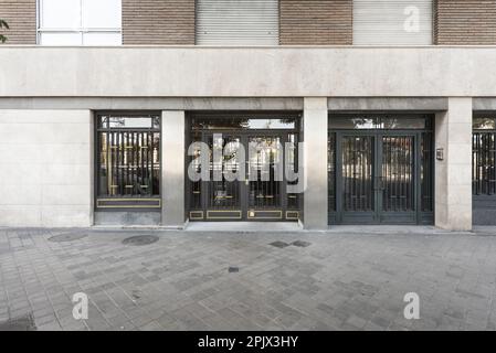 Außeneingang zur Straße eines einfachen Wohngebäudes mit lackierten Metalltüren und goldenen Details Stockfoto