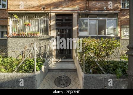 Zugang von der Straße zu einem bescheidenen Wohngebäude mit Blumenkästen auf beiden Seiten Stockfoto