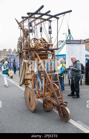 Eine Person auf Stelzen mit einem mobilen Gerät, das einen feuerspeienden Drachen trägt, wie sie etwa 2015 beim Skipton International Puppet Festival zu sehen ist. Stockfoto