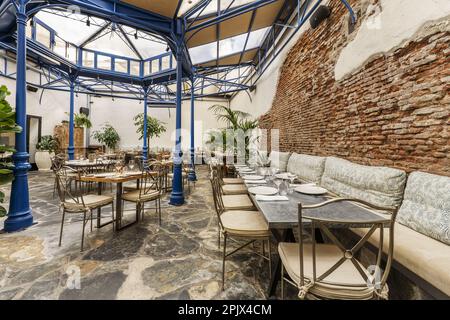 Der Speisesaal eines Restaurants ist im Industriestil eingerichtet und verfügt über ein großes Oberlicht mit einer Metallstruktur Stockfoto