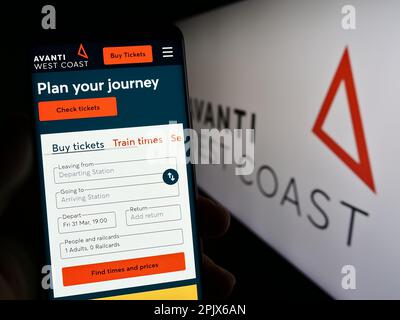 Person, die ein Mobiltelefon mit der Website des britischen Eisenbahnunternehmens Avanti West Coast auf dem Bildschirm vor dem Logo hält. Konzentrieren Sie sich auf die Mitte des Telefondisplays. Stockfoto