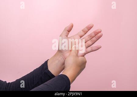 Nahaufnahme der Hand einer Frau, die ihre schmerzhafte Hand hält und an einem Bürosyndrom oder Neuropathie und Taubheitsgefühl in der Handfläche leidet. Stockfoto