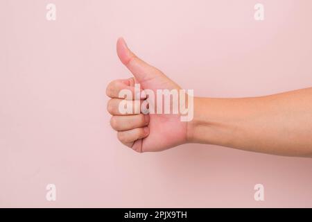 Nahaufnahme der männlichen Hand mit dem Symbol „Daumen nach oben“ auf pinkfarbenem Hintergrund. Stockfoto