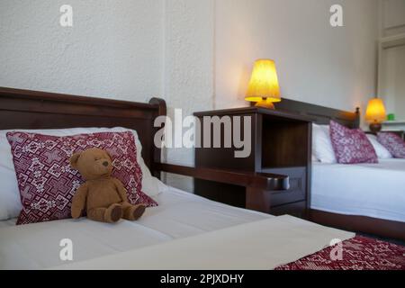 Schlafzimmer im Retro-Stil mit roten Kissen und braunem Teddybär auf dem Bett Stockfoto
