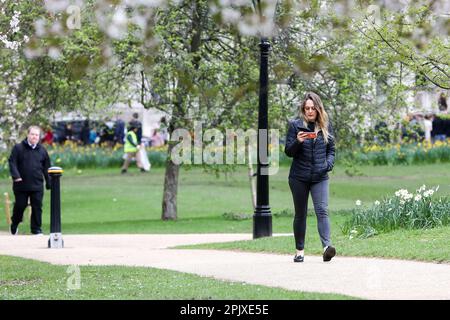 London, Großbritannien. 03. April 2023. Eine Frau schaut auf ihr Mobiltelefon, während sie im Frühling im St. James's Park im Zentrum von London spaziert. In den nächsten Tagen wird in London Frühlingssonne erwartet. (Foto: Steve Taylor/SOPA Images/Sipa USA) Guthaben: SIPA USA/Alamy Live News Stockfoto