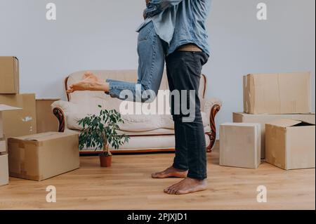 Nahaufnahme eines jungen Mannes in Jeans, einer Frau umgeben von Pappkartons, einem glücklichen afroamerikanischen Paar, das Spaß hat Stockfoto