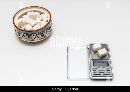 Ein Zuckerwürfel liegt in kleinem Maßstab. Zuckerkontrolle. Zuckerwürfel in einer Zuckerschüssel. Gesunder Lebensstil. Hochwertiges Foto. Stockfoto