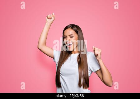 Porträt einer braunhaarigen, attraktiven, netten, aufgeregten jungen Dame, die den Sieg feiert, vor grauem Hintergrund, isoliert Stockfoto