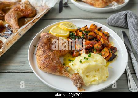 Im Ofen gebackene Hähnchenschenkel mit mariniertem Kürbissalat und Kartoffelpüree auf einem Teller Stockfoto