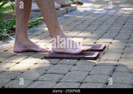 Alternative Medizin und Achtsamkeitspraxis, Nadel steht auf einem Sadhu-Brett, barfuß. Stockfoto
