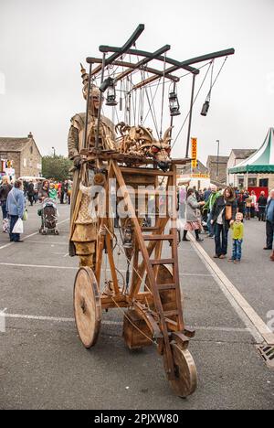 Person auf Stelzen mit einem mobilen Gerät, das einen feuerspeienden Drachen trägt, gesehen auf dem Skipton International Puppet Festival um 2015, Stockfoto