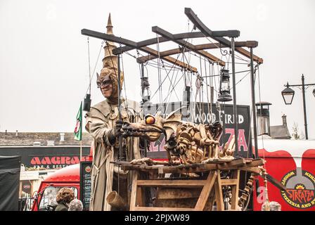 Person auf Stelzen mit einem mobilen Gerät, das einen feuerspeienden Drachen trägt, gesehen auf dem Skipton International Puppet Festival um 2015, Stockfoto