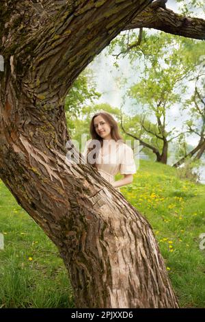 Eine schöne schwangere Frau geht in einem Garten spazieren Stockfoto
