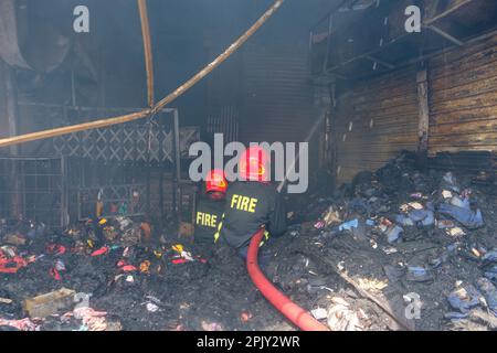 Feuerwehrleute versuchen, das Feuer auf dem Markt zu löschen. Im Morgengrauen des 4. April 2023 brach in Bangabazar, einem der größten Stoffmärkte in Dhaka, Bangladesch, ein massives Feuer aus. Dem Vernehmen nach begann der Brand in einer der Läden um ca. 6 UHR MORGENS und breitete sich schnell auf den Rest des Marktes aus. Das Feuer wütete fast 7 Stunden lang, bevor es unter Kontrolle gebracht wurde. Der Brand hat erhebliche Schäden am Markt verursacht, wobei die meisten Läden und Verkaufsstände durch die Flammen zerstört wurden. (Foto: Rizwan Hasan/Pacific Press) Stockfoto