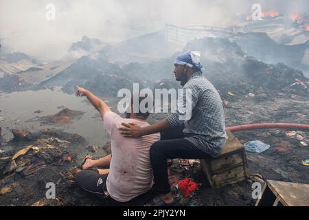 Deprimierte Ladenbesitzer sitzen verzweifelt, während das Feuer wütet.am 4. April 2023 brach in Bangabazar, einem der größten Stoffmärkte in Dhaka, Bangladesch, ein massives Feuer aus. Dem Vernehmen nach begann der Brand in einer der Läden um ca. 6 UHR MORGENS und breitete sich schnell auf den Rest des Marktes aus. Das Feuer wütete fast 7 Stunden lang, bevor es unter Kontrolle gebracht wurde. Der Brand hat erhebliche Schäden am Markt verursacht, wobei die meisten Läden und Verkaufsstände durch die Flammen zerstört wurden. (Foto: Rizwan Hasan/Pacific Press) Stockfoto