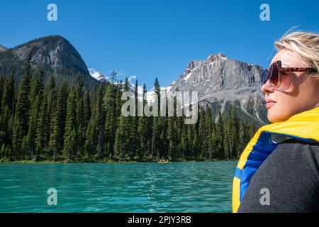 Eine blonde Frau blickt in die Ferne, denkt und reflektiert während einer Kanufahrt auf dem Emerald Lake im Yoho National Park Canada