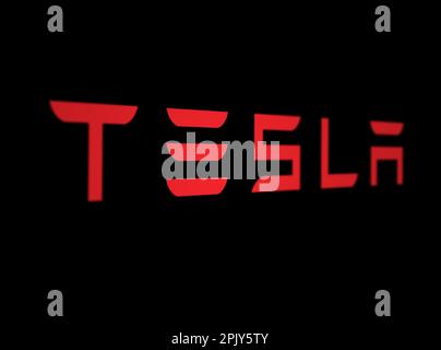 New York, USA, März 2023: Rotes Tesla Logo auf schwarzem Hintergrund. Tesla ist ein amerikanisches multinationales Automobil- und Energieunternehmen. Illustrierend e Stockfoto