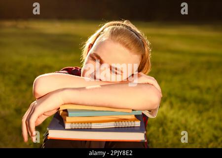 Ich bin es leid, den Schüler zu studieren, der im Park auf seinen Büchern eingeschlafen ist Stockfoto