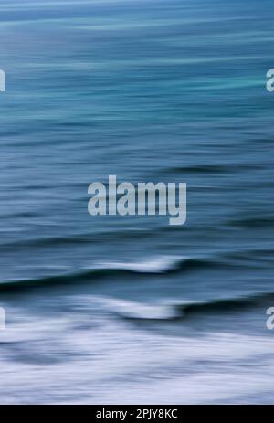 Lange Wellenbelastung und Flut, die sich einem Strand nähert Stockfoto