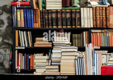 Stapel von vielen alten gebrauchten Büchern und Magazinen, die in einem lokalen Antiquarienbuchladen ausgestellt werden Stockfoto