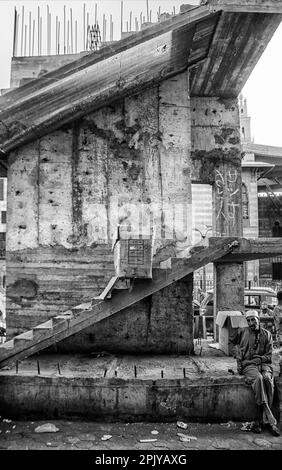 Ein Mann, der auf einer unvollendeten Brücke saß. Das Stadtzentrum von Kairo tagsüber mit Verkäufern und Verkehr. Ägypten. Stockfoto