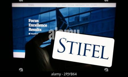 Person, die ein Handy mit dem Logo der amerikanischen Investmentgesellschaft Stifel Financial Corp. Auf dem Bildschirm vor der Webseite hält. Konzentrieren Sie sich auf das Display des Telefons. Stockfoto