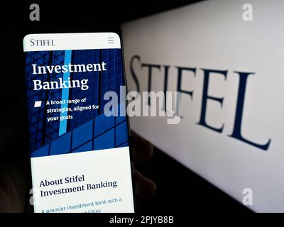 Person, die ein Mobiltelefon besitzt, mit Webseite der US-amerikanischen Investmentgesellschaft Stifel Financial Corp. Auf dem Bildschirm mit Logo. Konzentrieren Sie sich auf die Mitte des Telefondisplays. Stockfoto