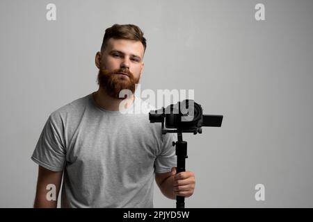 Videofilmer, der mit Steadicam gute Aufnahmen macht. Kameramann Schöpfer mit einem Stabilisator in den Händen nimmt ein Video auf der slr-Videokamera auf weiß Stockfoto