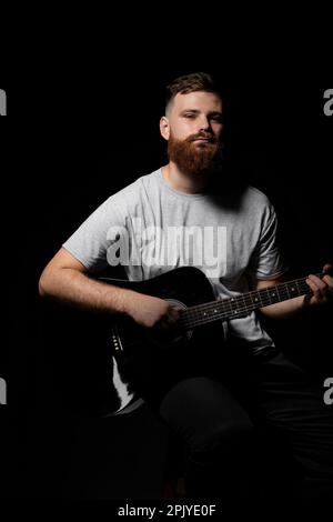 Porträt eines jungen, bärtigen, gutaussehenden Gitarristen, Künstlers, Komponisten, Pop-Rocker-Stars. Musikkonzept. Stockfoto