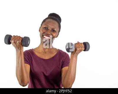 Junge Frau, die zwei Kurzhanteln hebt, isoliert auf weißem Hintergrund Stockfoto