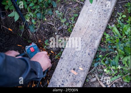 Detailansicht des Arbeiters, der einen Metallzaun mit einem Winkelschleifer entfernt. Stockfoto