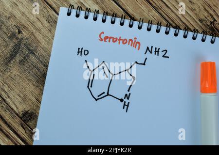 Konzept des chemisch-molekularen formulierungshormons Serotonin auf Buch isoliert auf Holztisch. Stockfoto