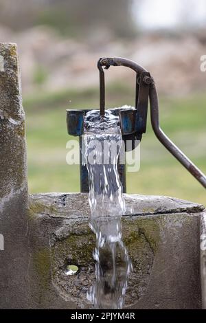 Eine alte Pumpe wurde verwendet, um Wasser aus dem Feld in der Türkei zu extrahieren. Retro-Brunnenpumpe, alte manuelle Wasserpumpe (Hebel). Gusseisenwasserpumpe im Vintage-Stil. 4K-Videoaufnahme. Stockfoto