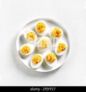 Gefüllte Eier mit Paprika, Senf und Mayonnaise auf dem Teller auf weißem Steinhintergrund. Draufsicht, flach liegend Stockfoto