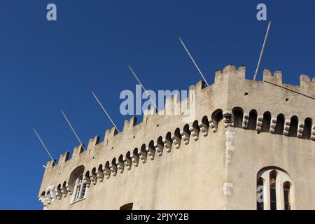 Steinfassade eines Teils des Château Grimaldi auf dem Stadtplatz Haut de Cagnes an einem klaren, blauen Himmel am Nachmittag mit leeren Fahnenstangen (Cagnes sur Mer, Frankreich) Stockfoto
